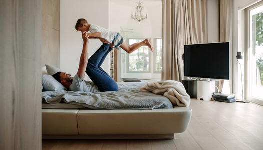 Father playing in bed with son