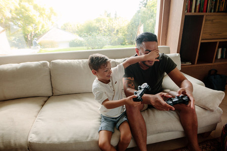 Father and son having fun playing video games at home