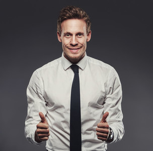 Enthusiastic businessman giving the thumbs up against a grey background