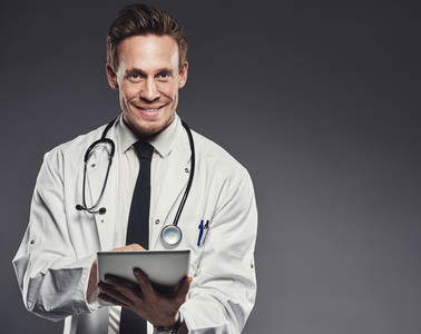 Smiling doctor with stethoscope and tablet