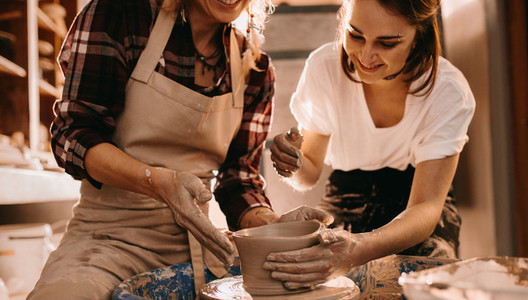 Two women at a pottery workshop making clay pots