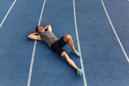 Sprinter relaxing by lying on the running track