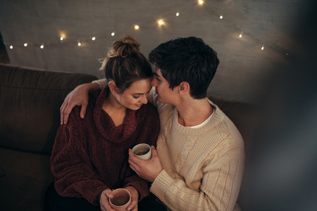 Cozy couple sitting together on sofa with coffee