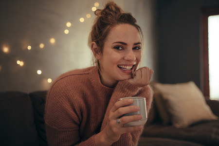 Smiling woman sitting at home with a cup of coffee
