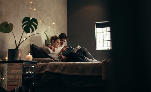 Couple reading book together on bed