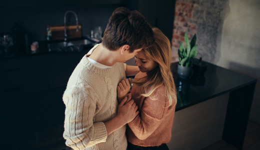 Romantic young couple embracing in the kitchen at home