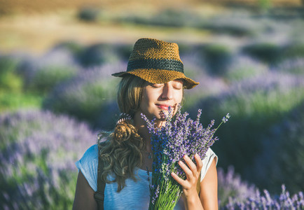 Young girl wearing straw hat with bouquet of lavender flowers
