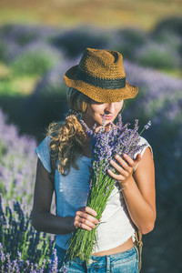 Girl wearing straw hat with bouquet of lavender flowers