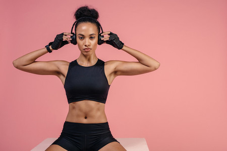 Fit woman with headphones sitting on box after workout