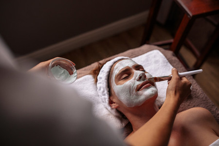 Cosmetician applying facial mask
