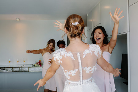Bride and bridesmaids having fun in hotel room on wedding day