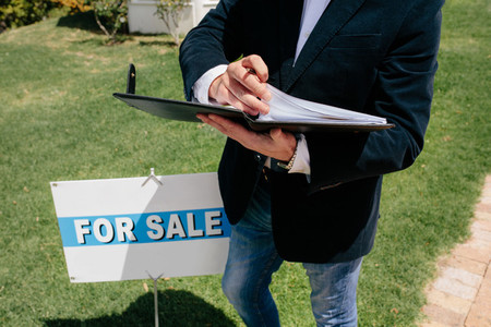 Real estate agent standing by signboard