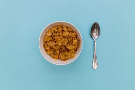 Breakfast cereal cornflakes in bowl with silver spoon