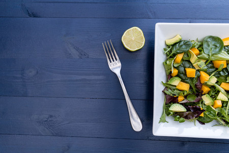 Healthy mango avocado salad with fork lime and copy space