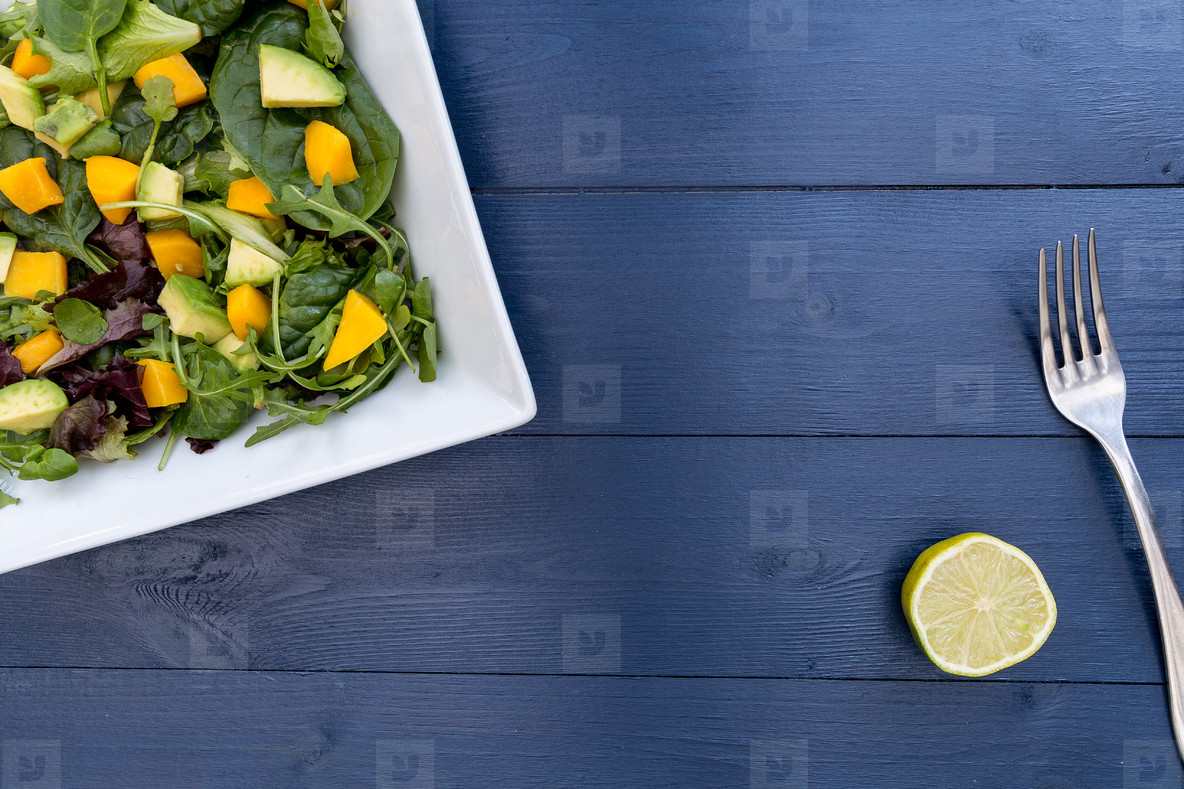 Lunch plate of mango avocado salad on blue wood table