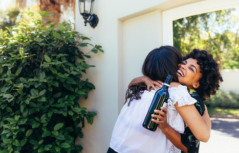 Woman with wine bottle congratulating friend for new house
