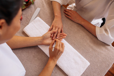 Woman hands receiving manicure and nail care procedure
