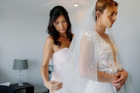 Bridesmaid helping bride to put on a veil