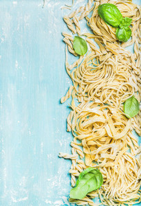 Different kinds of homemade fresh Italian pasta with green basil