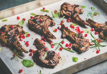 Grilled lamb ribs with pomegranate seeds and herbs in tray