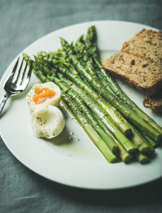 Cooked asparagus with soft boiled egg  grilled bread toasts and herbs