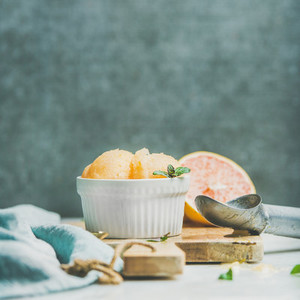 Pink grapefruit sorbet with mint in bowl on wooden board