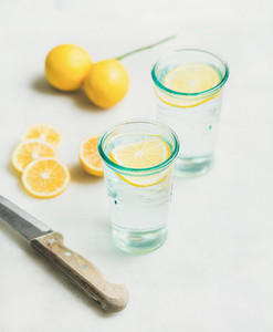 Morning detox lemon water in glasses and fresh lemons