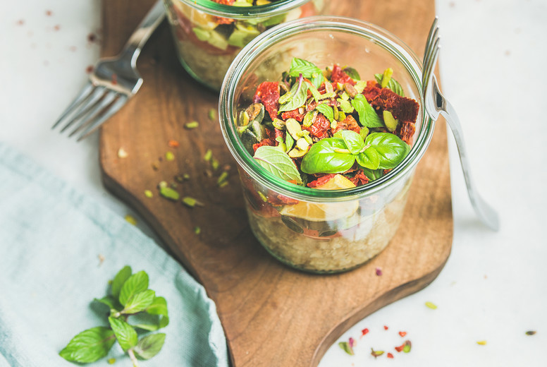 Healthy salad with quionoa, avocado, dried tomatoes on wooden board