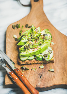 Healthy green veggie sandwich with avocado on board