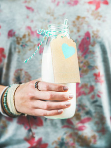 Young woman holding bottle of dairy free almond milk in hand