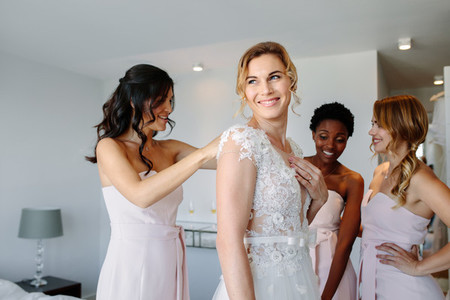 Friends dressing the bride for wedding