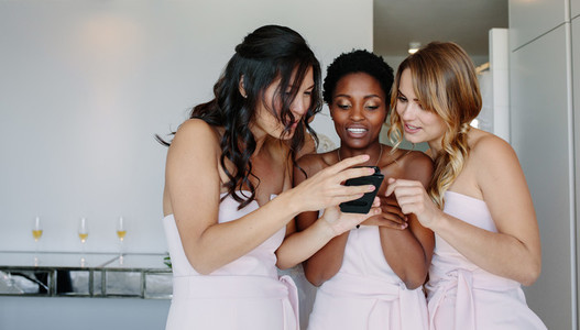 Beautiful bridesmaids on the wedding day looking at mobile phone