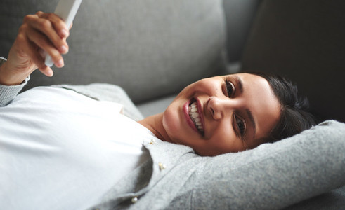 Woman laying on couch looking sideways smiling