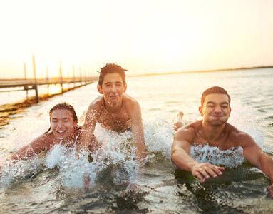 Three young boys splashing through the water