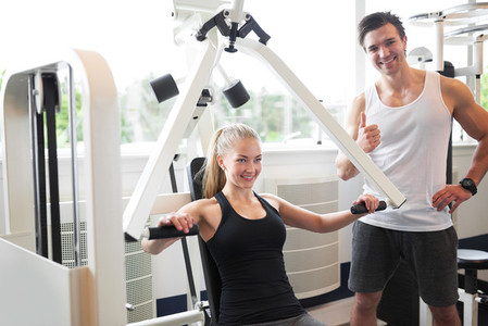 Trainer Assisting Woman Doing Chest Press Exercise