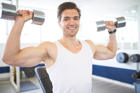 Muscular Man Lifting Two Dumbbells in the Gym