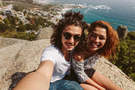 happy couple taking selfie on top of mountain