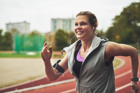 Smiling woman running on track field