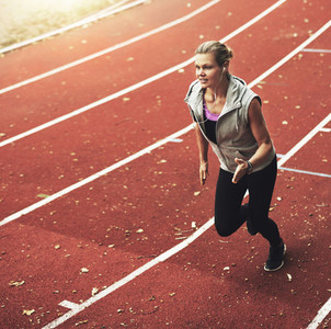 Portrait of young sportswoman running fast on track field