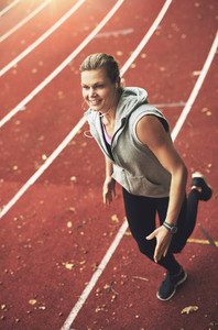 Young female athlete running fast on stadium