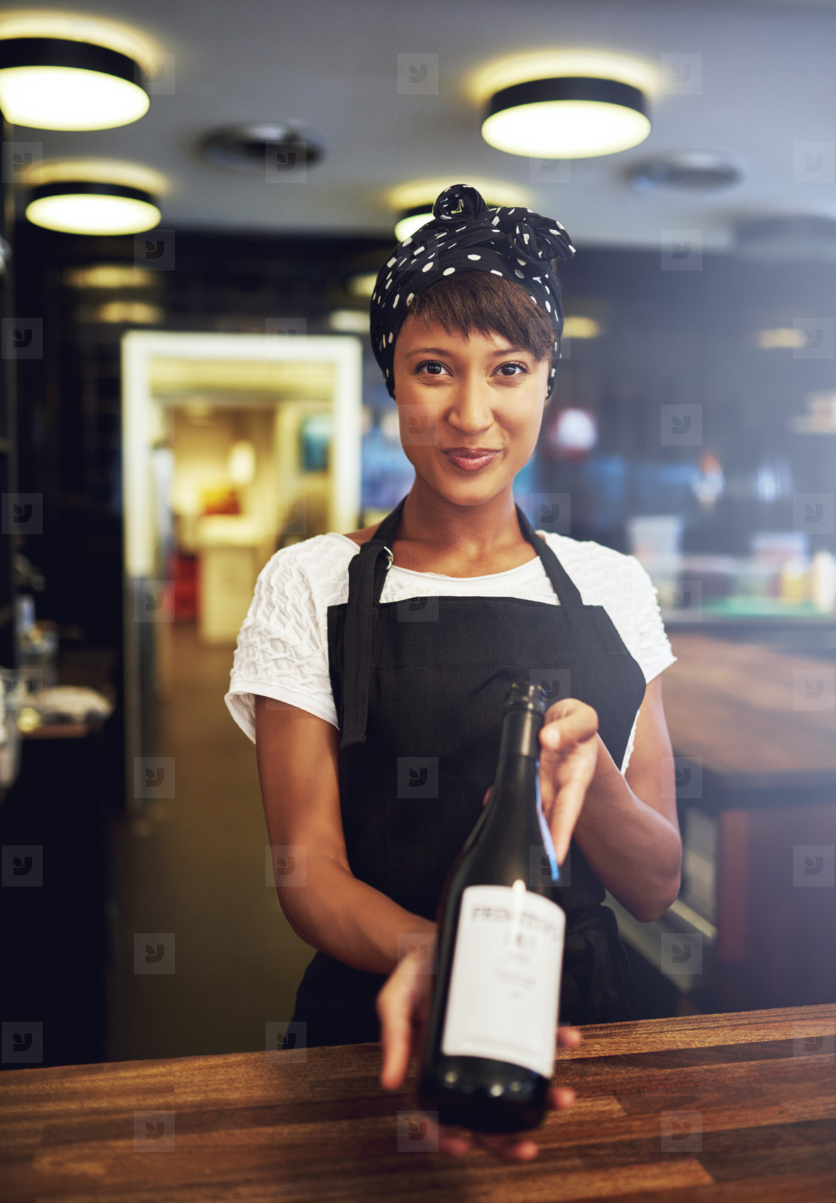 Smiling young waitress presenting a bottle of wine