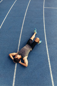 Sprinter relaxing by lying on the running track