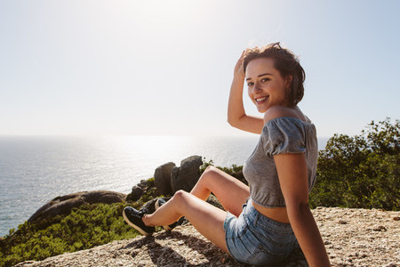 Smiling woman sitting on the top of mountain