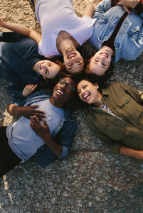 Diverse friends lying on ground in circle outdoors