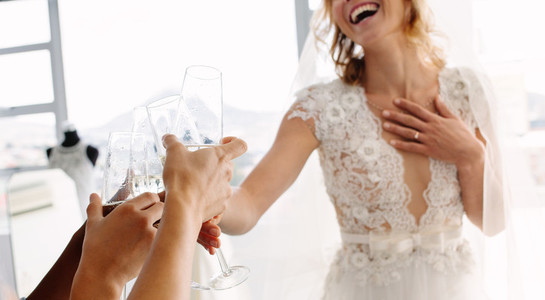 Bride with friends drinking champagne in bridal boutique