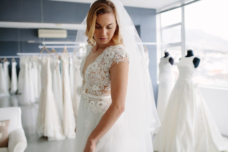 Beautiful woman trying on bridal gown in boutique