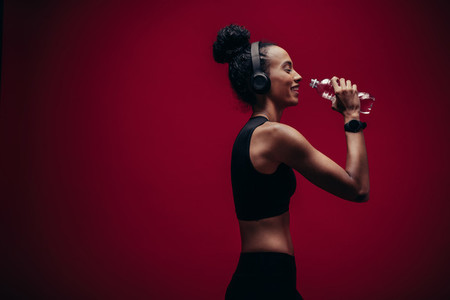 Fitness woman drinking water after workout