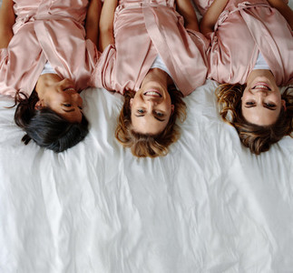 Three young women lying on bed and smiling