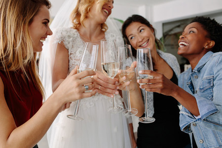 Woman in bridal gown toasting champagne glasses with friends
