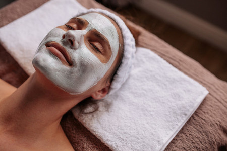 Woman with cosmetic face mask in spa